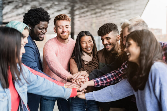 Young multiracial friends stacking hands together outdoor - Friendship and diversity