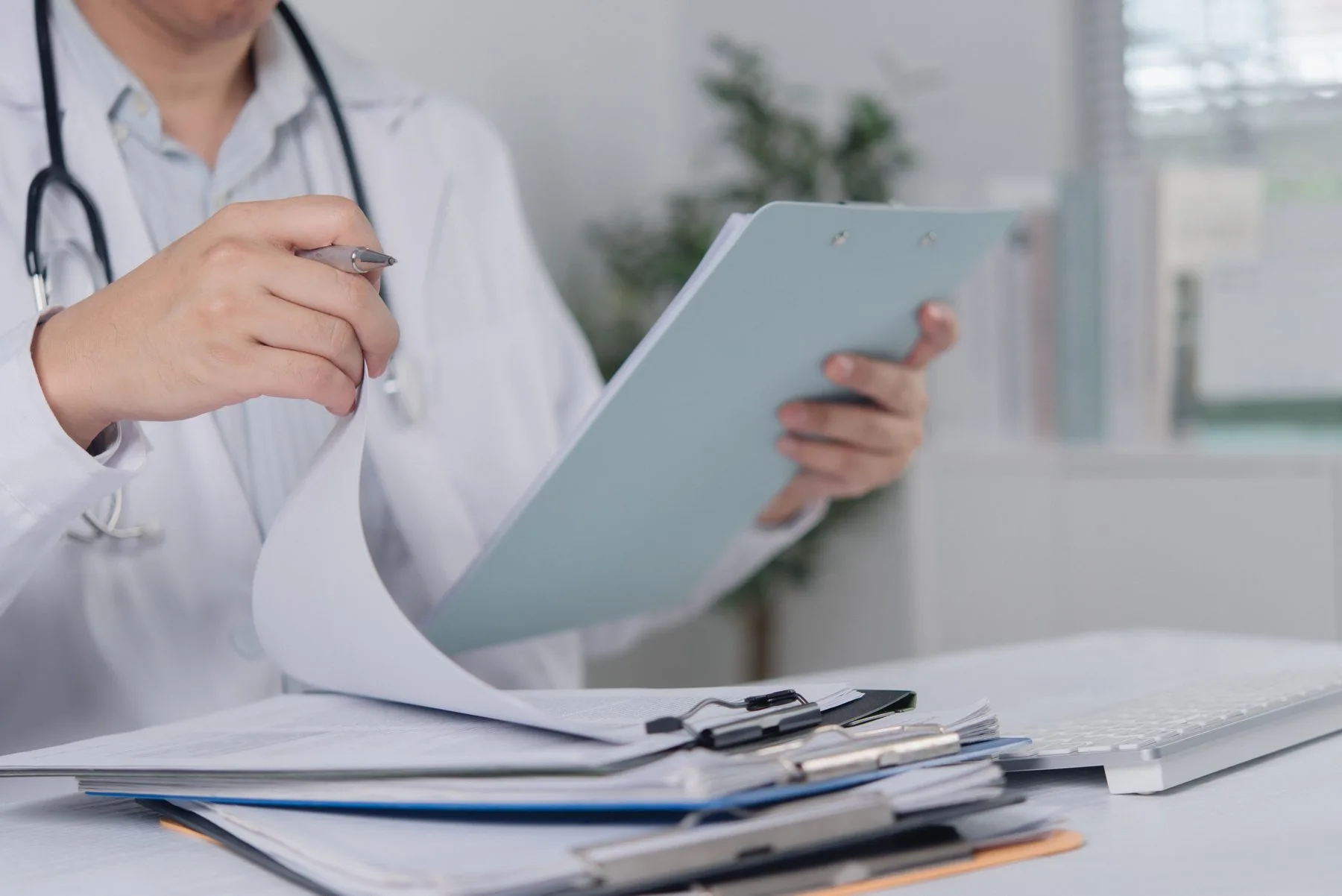 Clinician reviewing a stack of printed protocol documents on a clipboard